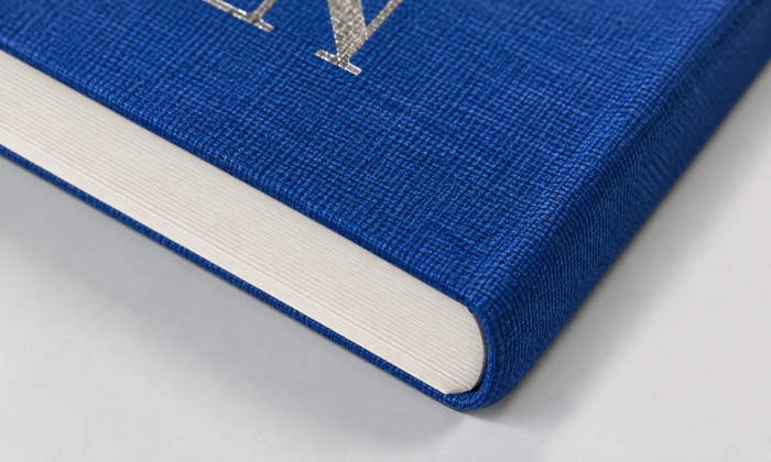 Close-up of a cobalt blue cloth-covered flexibound book showing the rounded corner, cover overhang, and page block