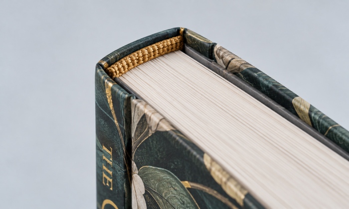 Close-up of a woven headband attached across the top of a case-bound book block beneath the cover overhang